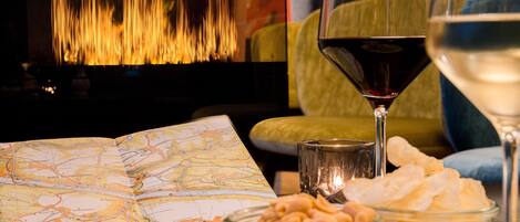 A map, a glass of red wine, and a bowl of nuts on a table.