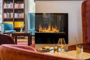 A cozy living room with a fireplace, a bookshelf, and a dining area with a table set for two.