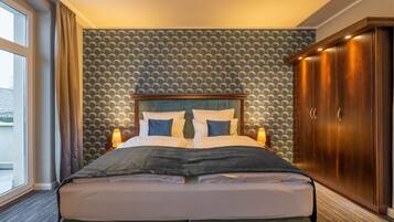 A hotel room with a large bed, a wardrobe, and a patterned wallpaper.