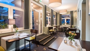 Una habitación de hotel con zona de comedor, ventanas amplias y una escalera que lleva a un espacio al aire libre.