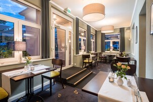 A hotel room with a dining area, large windows, and a staircase leading to an outdoor area.