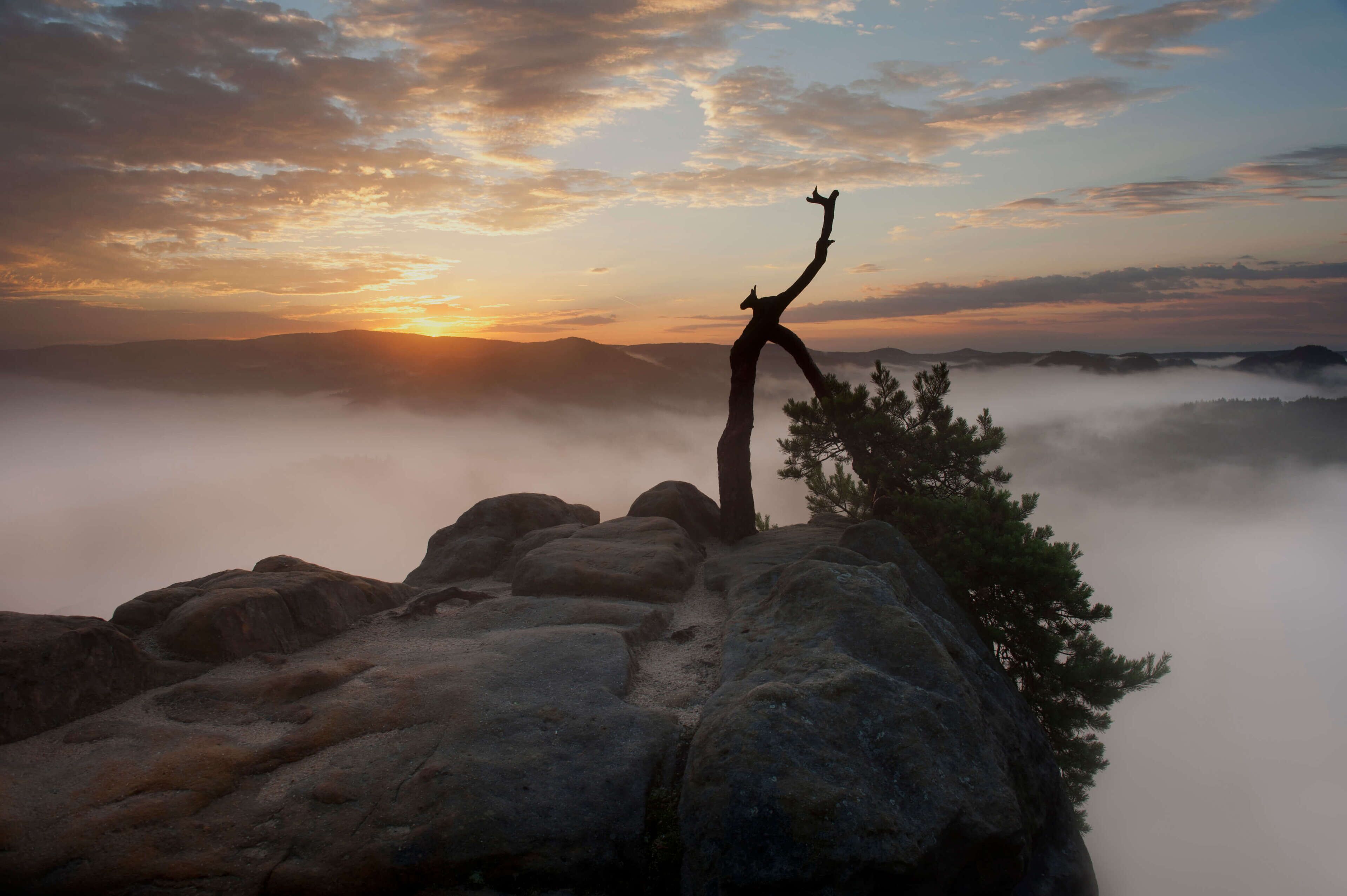 A rocky landscape with a silhouette of a person standing on a rock formation.