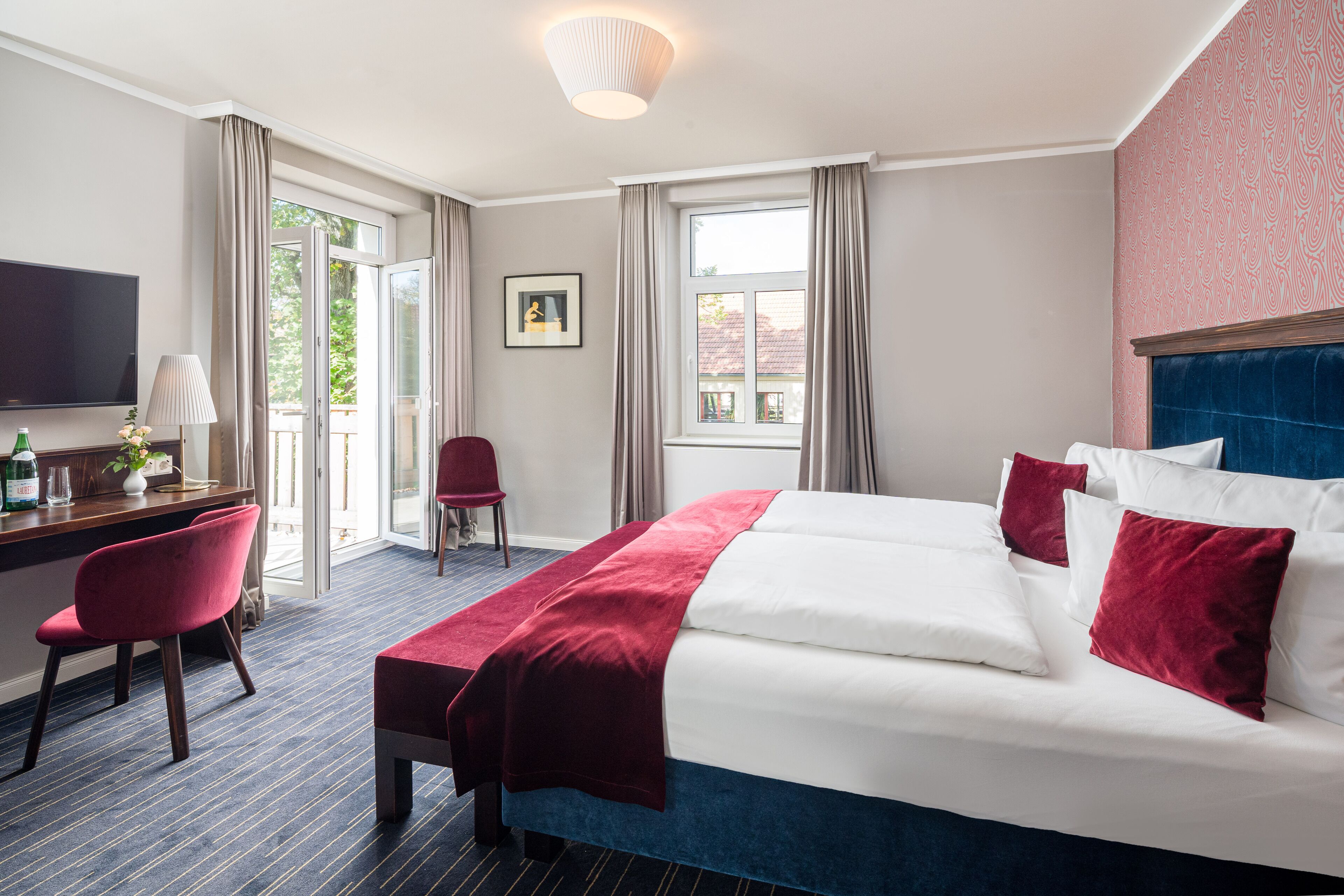 Ein Hotelzimmer mit einem großen Bett, einem Schreibtisch, einem Stuhl und einem Fernseher.