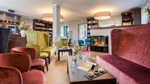 Un área de estar moderna con chimenea, asientos cómodos, una mesa de centro con aperitivos y una estantería.