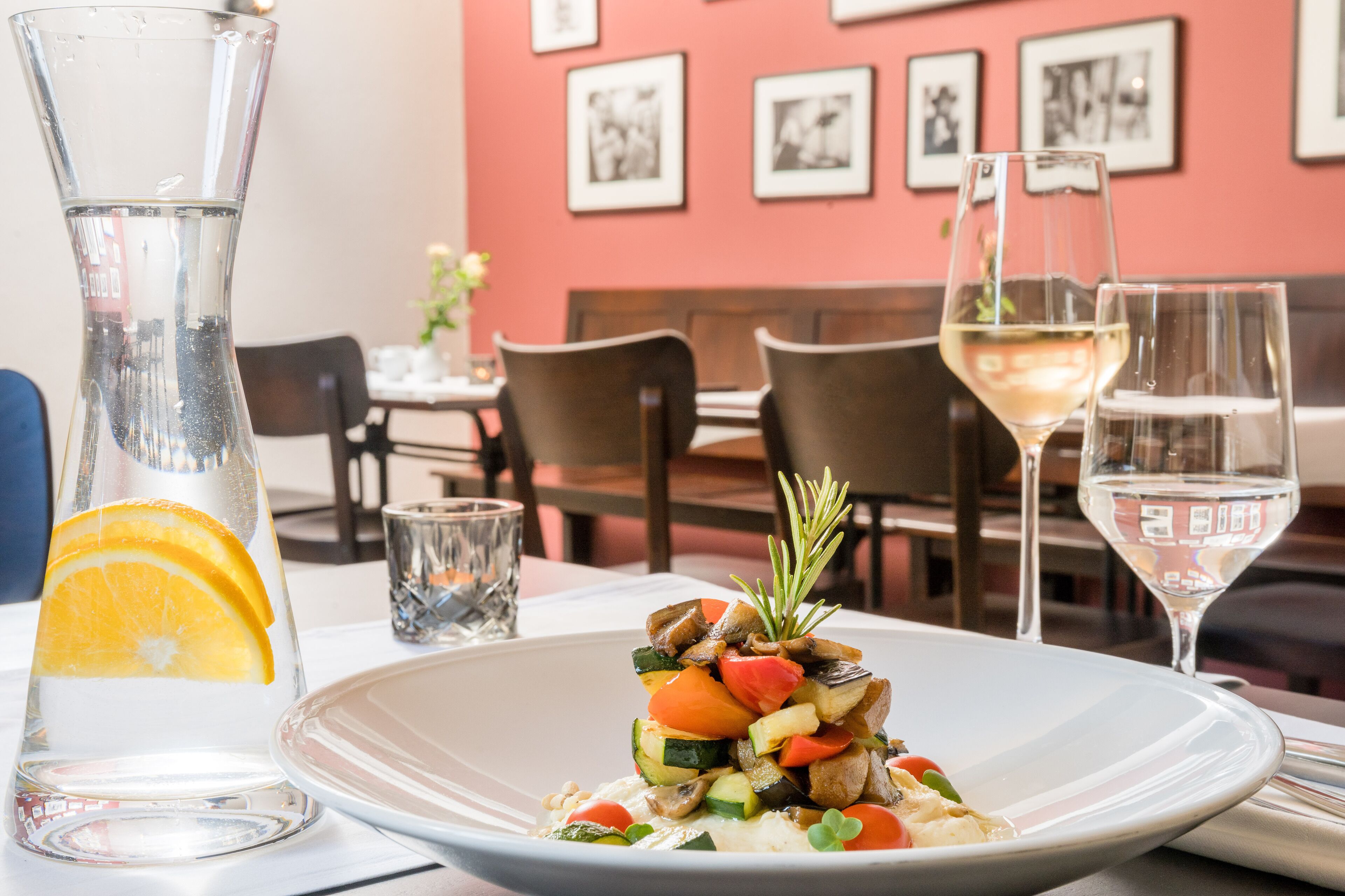 Una mesa de comedor con un plato de comida, un vaso de agua y una copa de vino.