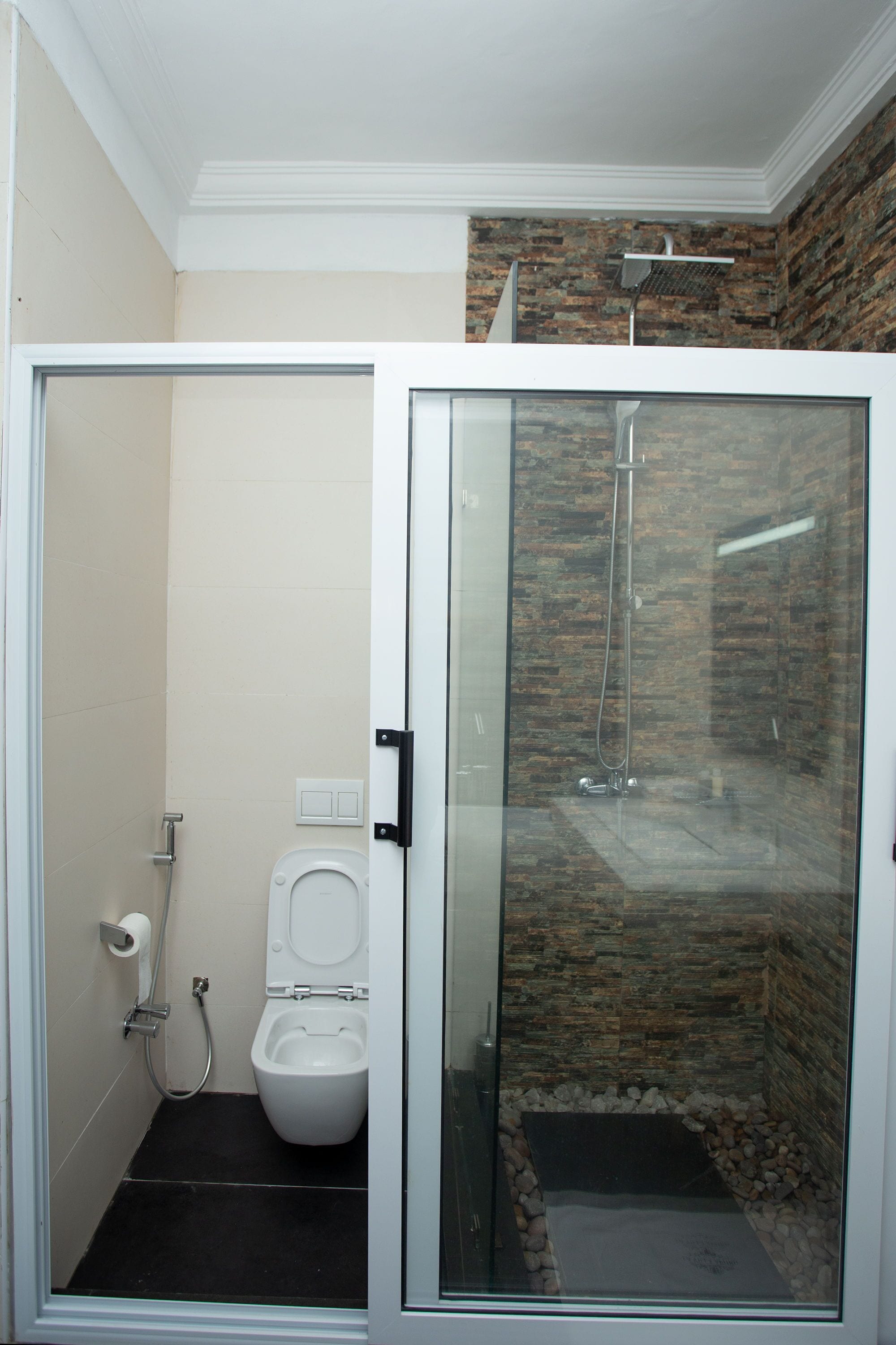 Un baño moderno con ducha de vidrio, inodoro y lavamanos blanco.