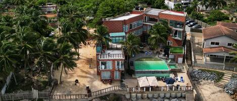 A coastal hotel with multiple buildings, a swimming pool, and a beach area.