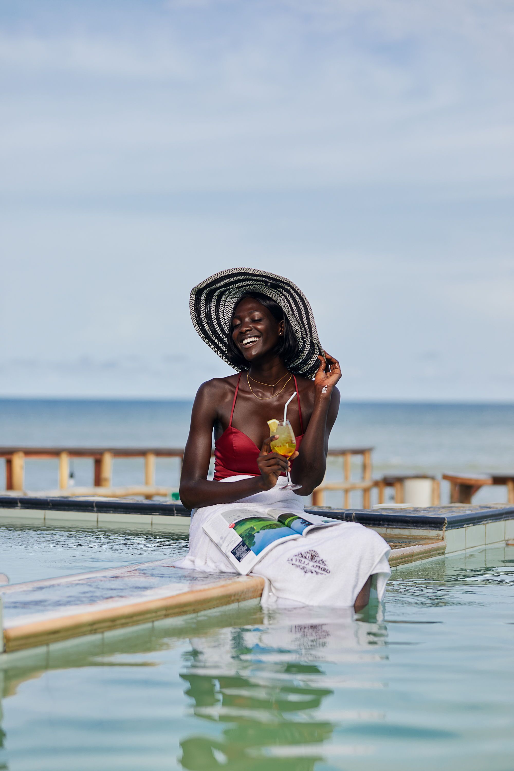 Una persona sentada en una piscina con vista al océano.