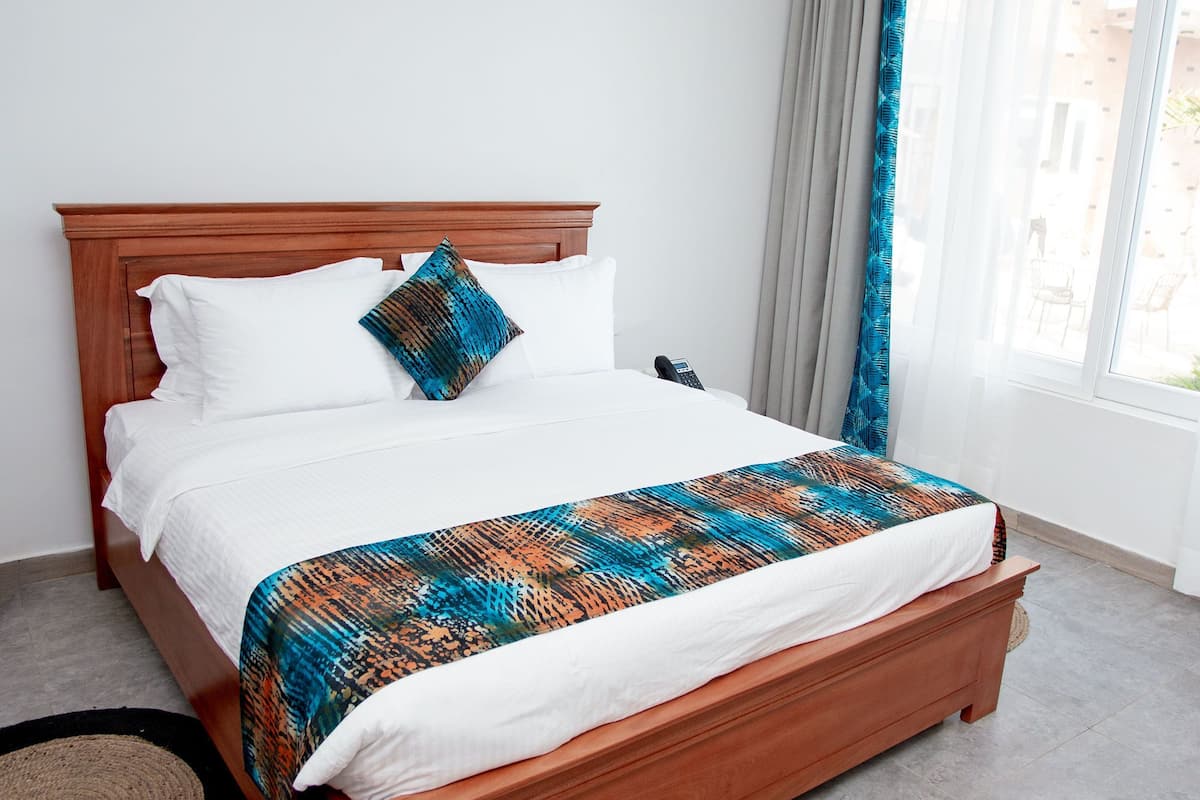 Una cama bien hecha con una colcha estampada, un cabecero de madera y una mesita de noche con una lámpara.