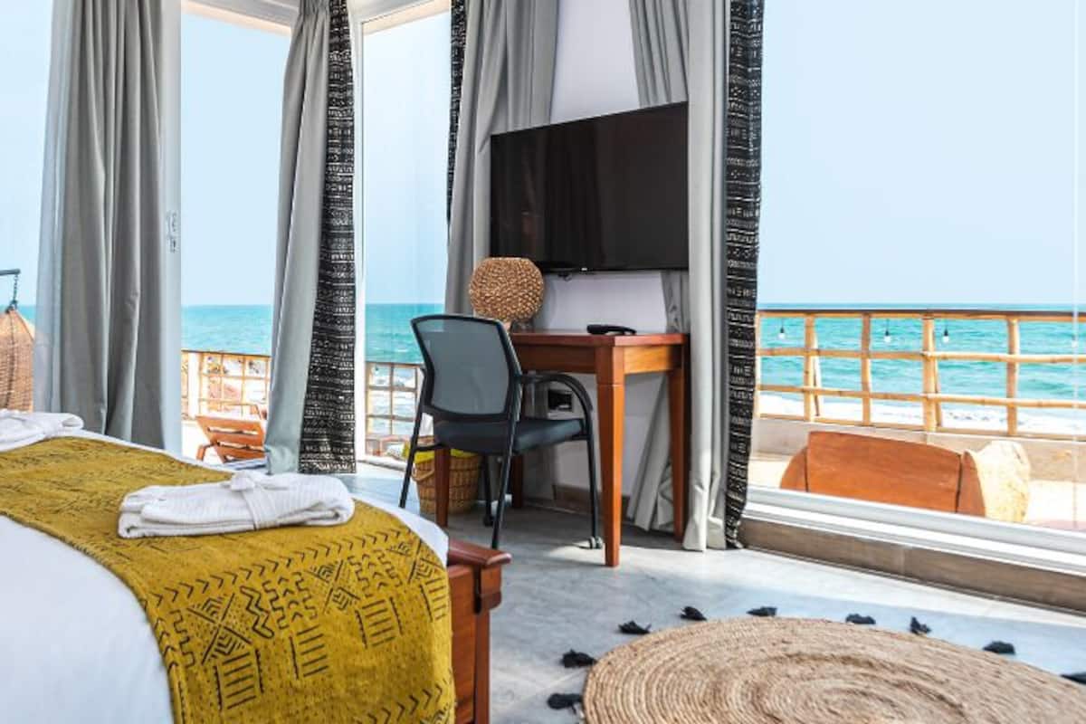 Habitación de hotel con cama, escritorio, televisor y vista al mar.