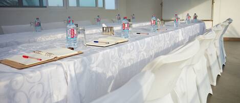 A conference room with a long table set for a meeting, equipped with water bottles, notepads, and pens.