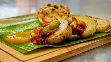 Una tabla de madera con papas en rodajas y un vegetal relleno sobre una hoja verde.