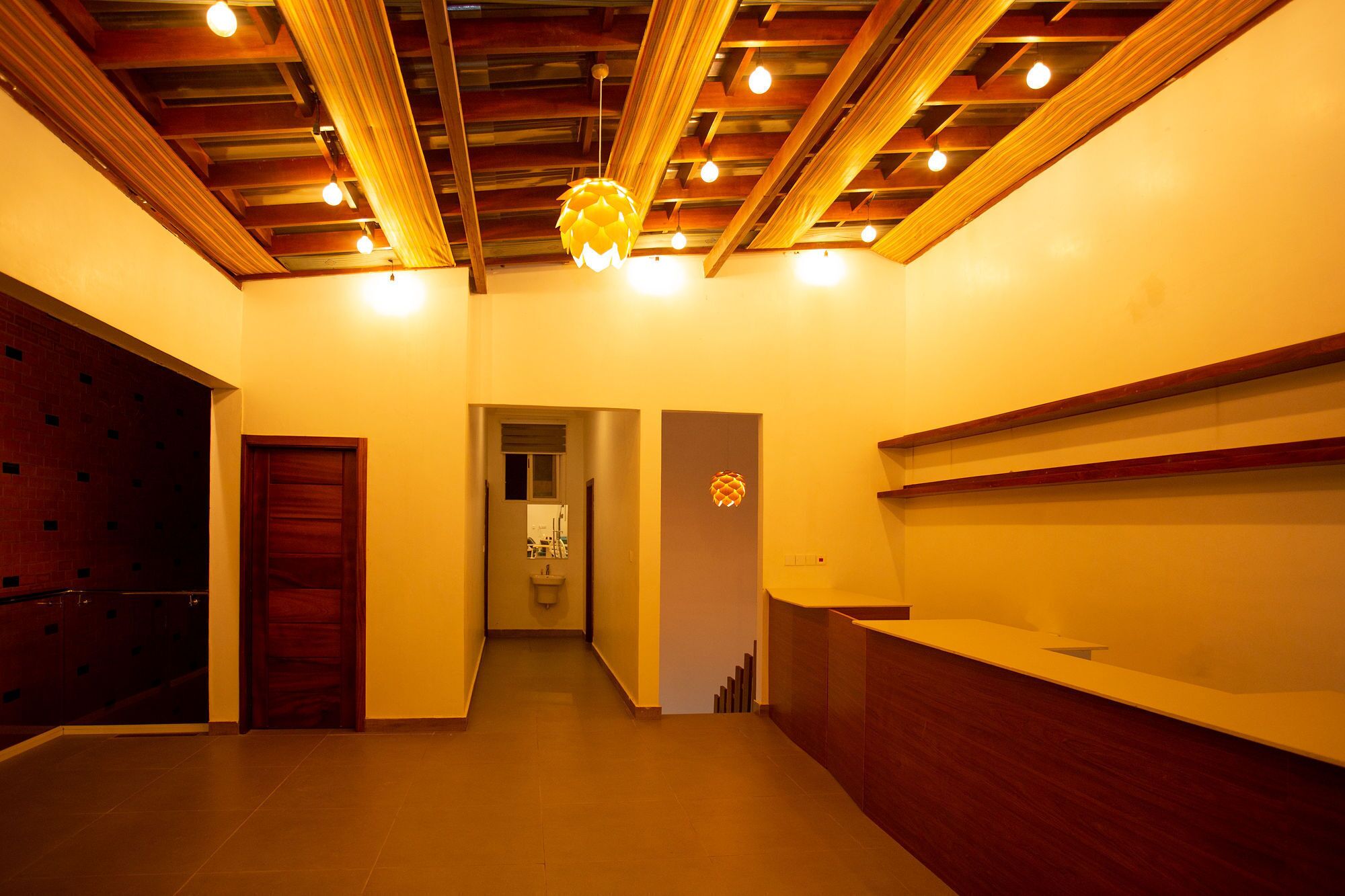 A reception area with a wooden reception desk, a wall-mounted telephone, and a door leading to a bathroom.