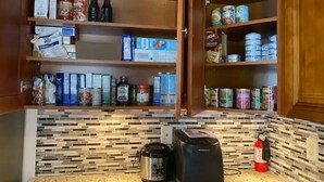 Une cuisine avec des meubles en bois, un plan de travail en granit, ainsi que divers produits alimentaires et appareils électroménagers.