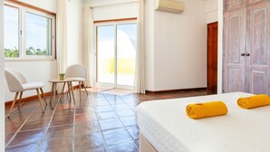 A hotel room with a bed, a chair, a small table, and a sliding glass door leading to a balcony. - Peaceful villa with heatable pool in Galé (Albufeira)