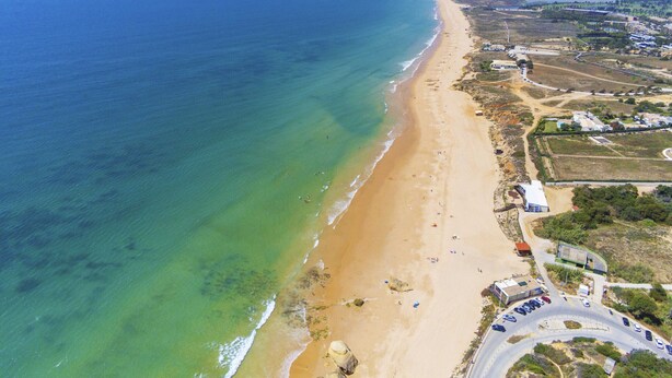 An aerial view of a coastal area with a sandy beach, a road with vehicles, and buildings in the distance. - Peaceful villa with heatable pool in Galé (Albufeira)