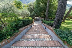 Un sendero de ladrillo que atraviesa un exuberante jardín con árboles y setos.