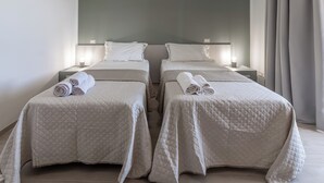Une chambre d’hôtel avec deux lits, chacun recouvert d’une courtepointe matelassée et agrémenté de serviettes roulées.