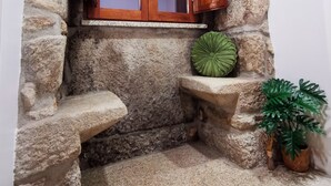 A stone wall with a wooden cabinet and a small bench. - CASA DO PENEDO CASTLE HOUSE (Linhares da Beira)