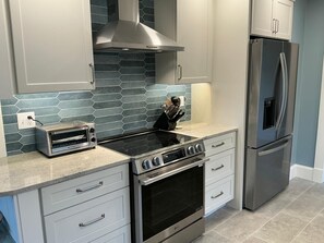A modern kitchen with a built-in oven, a stainless steel refrigerator, and a toaster on the countertop. - Panoramic Ocean View; walk to private beach (Gloucester)