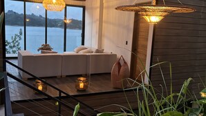 Un intérieur moderne avec un canapé placé face à une grande fenêtre donnant sur un plan d’eau.