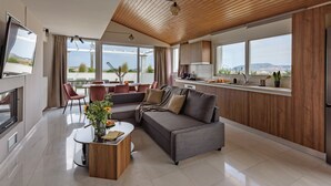 Ein modernes Wohnzimmer mit einem grauen Sofa, einem Couchtisch und einem Essbereich mit roten Stühlen.