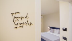 A hotel room with a bed, a wall-mounted sign, and a bedside table. - Mazzini Palace (Misterbianco)