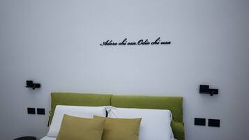 Una cama con cabecera verde, almohadas blancas y mostaza, y luces negras fijadas a la pared.