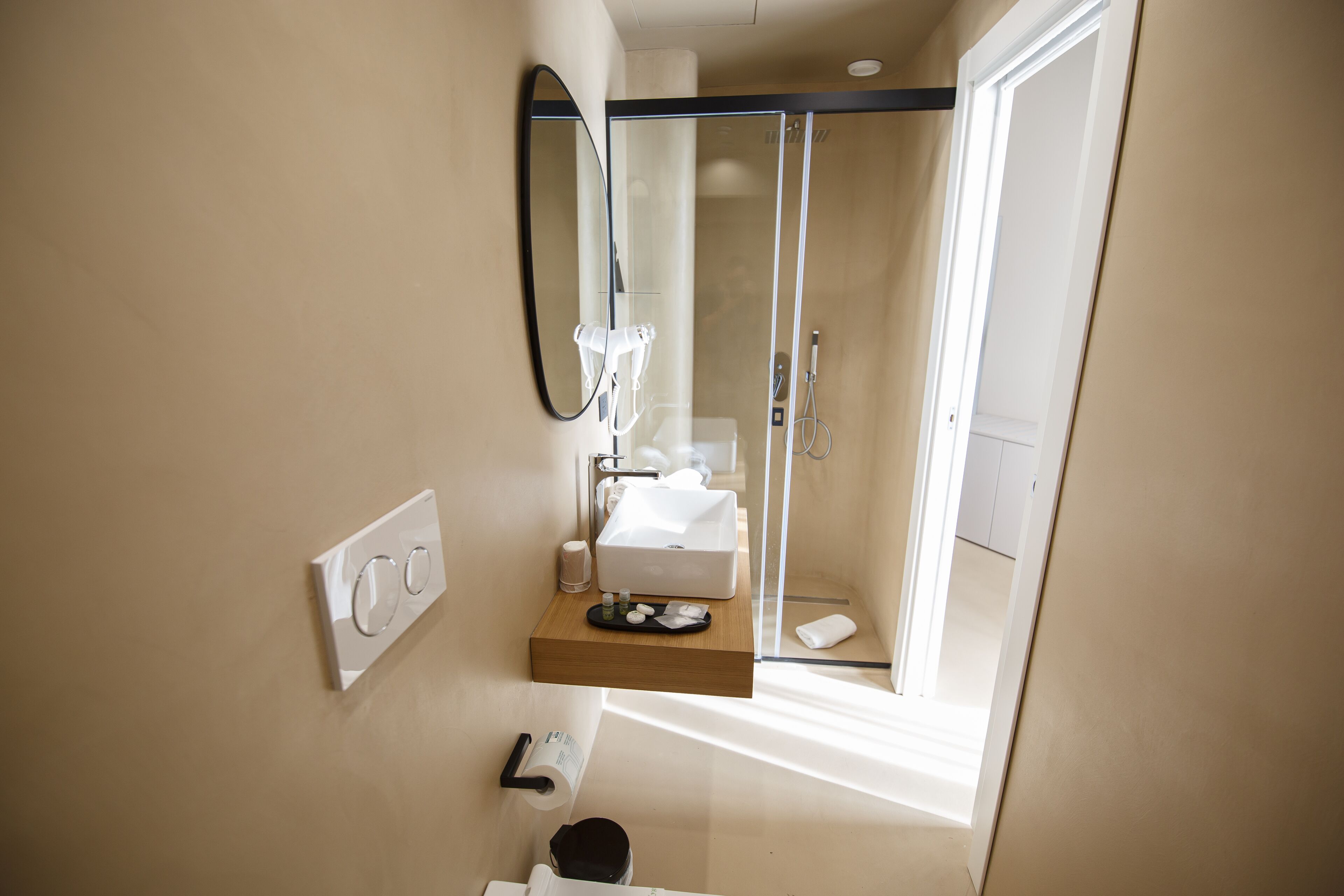 A modern bathroom with a glass shower enclosure, a white sink, and a mirror.