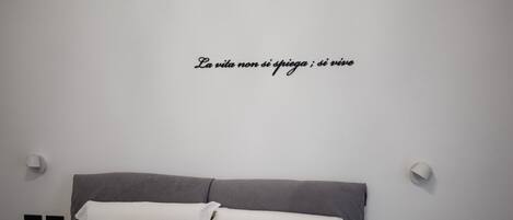 Una cama bien hecha con cabecera gris, dos almohadas blancas y dos almohadas marrones.
