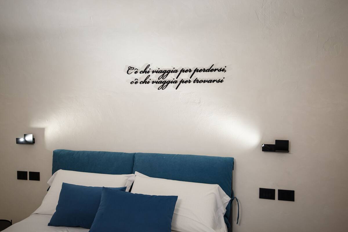 A bedroom with a bed, pillows, and a wall with a motivational quote.