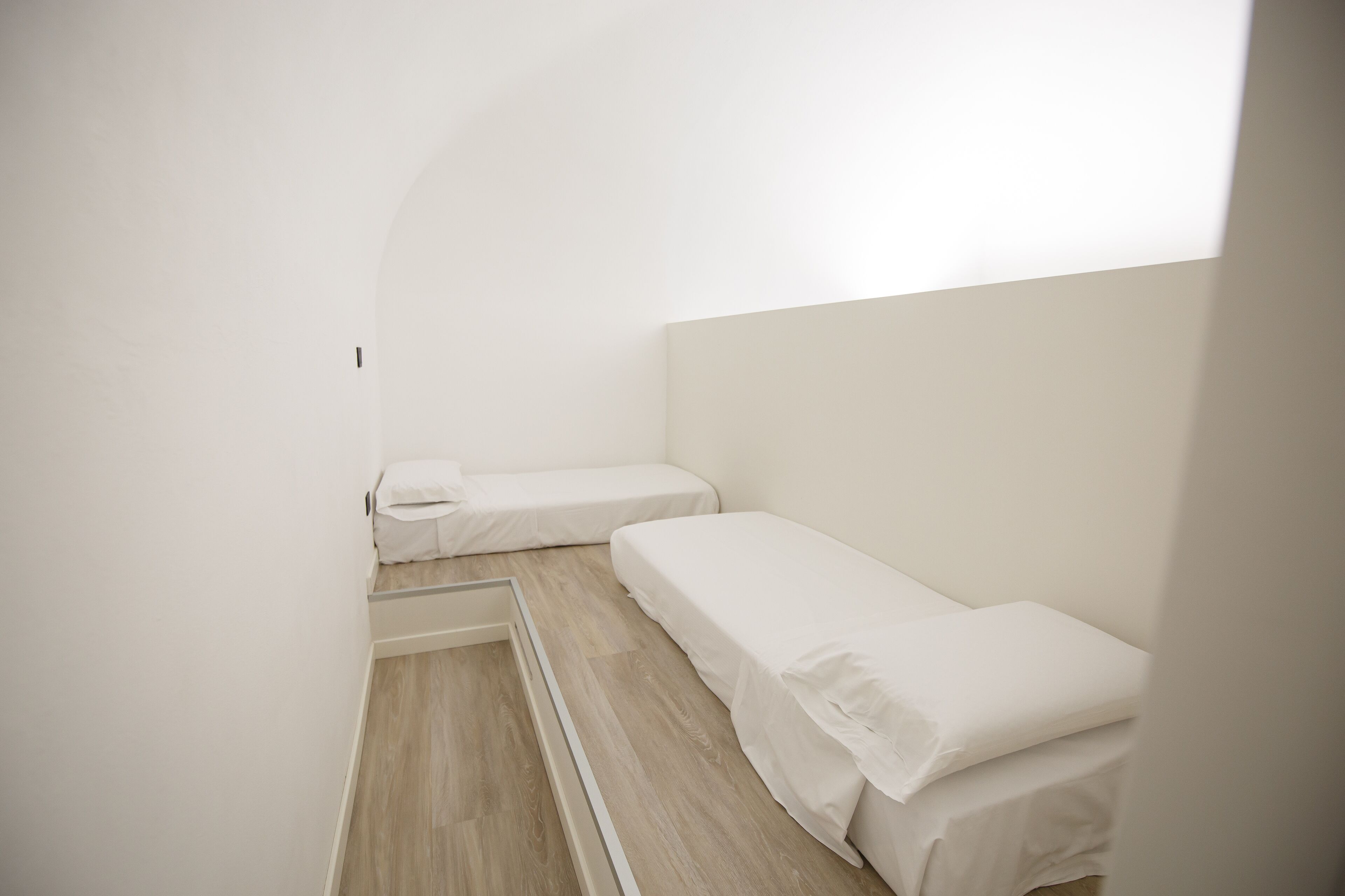 Una habitación pequeña y limpia con dos camas individuales y suelo de madera.