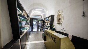 A reception area with a modern design, featuring a reception desk labeled "MAZIN PALACE" and a view into the adjacent shop area. - Mazzini Palace (Misterbianco)