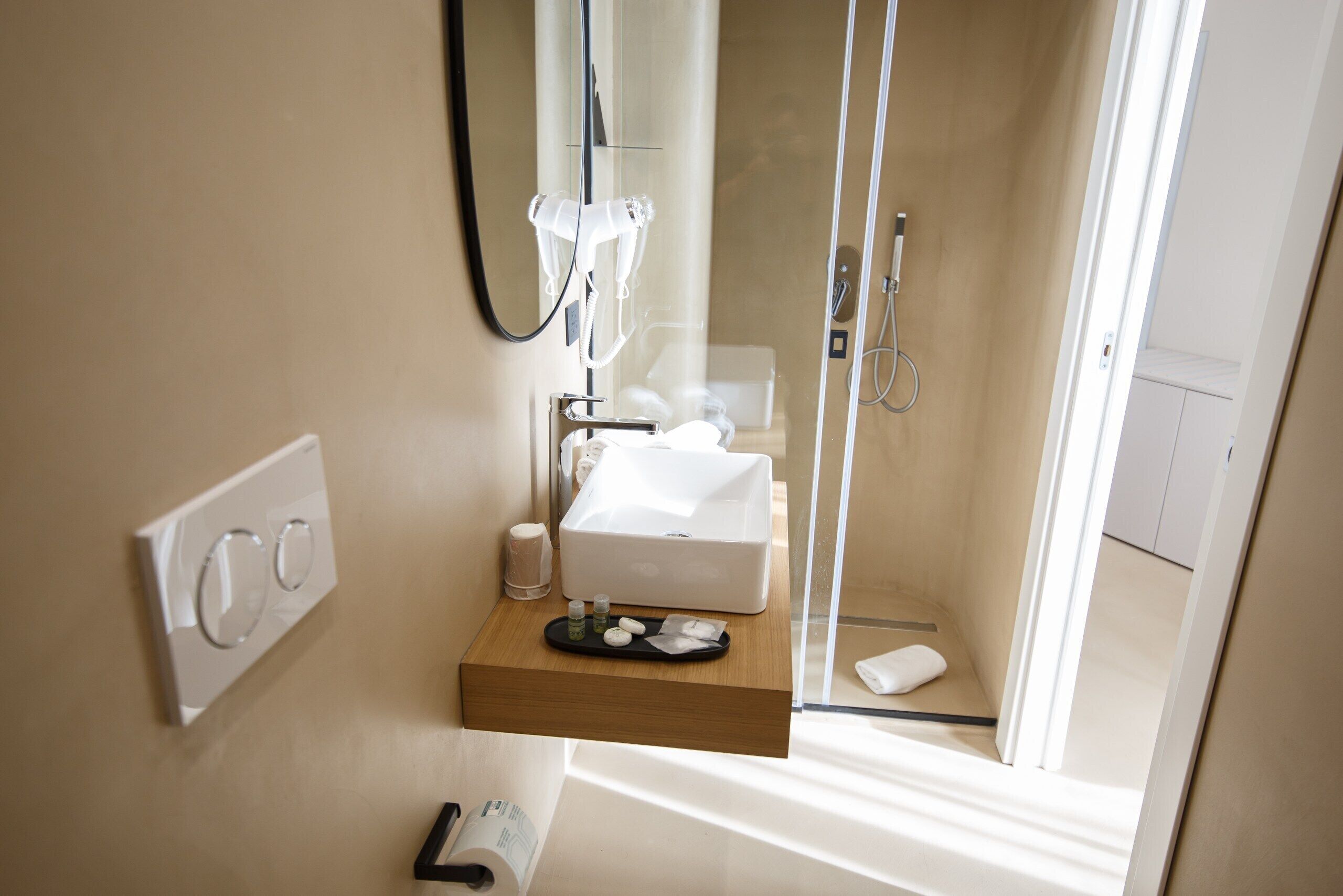 A modern bathroom with a glass shower enclosure, a white sink, and a wooden vanity.