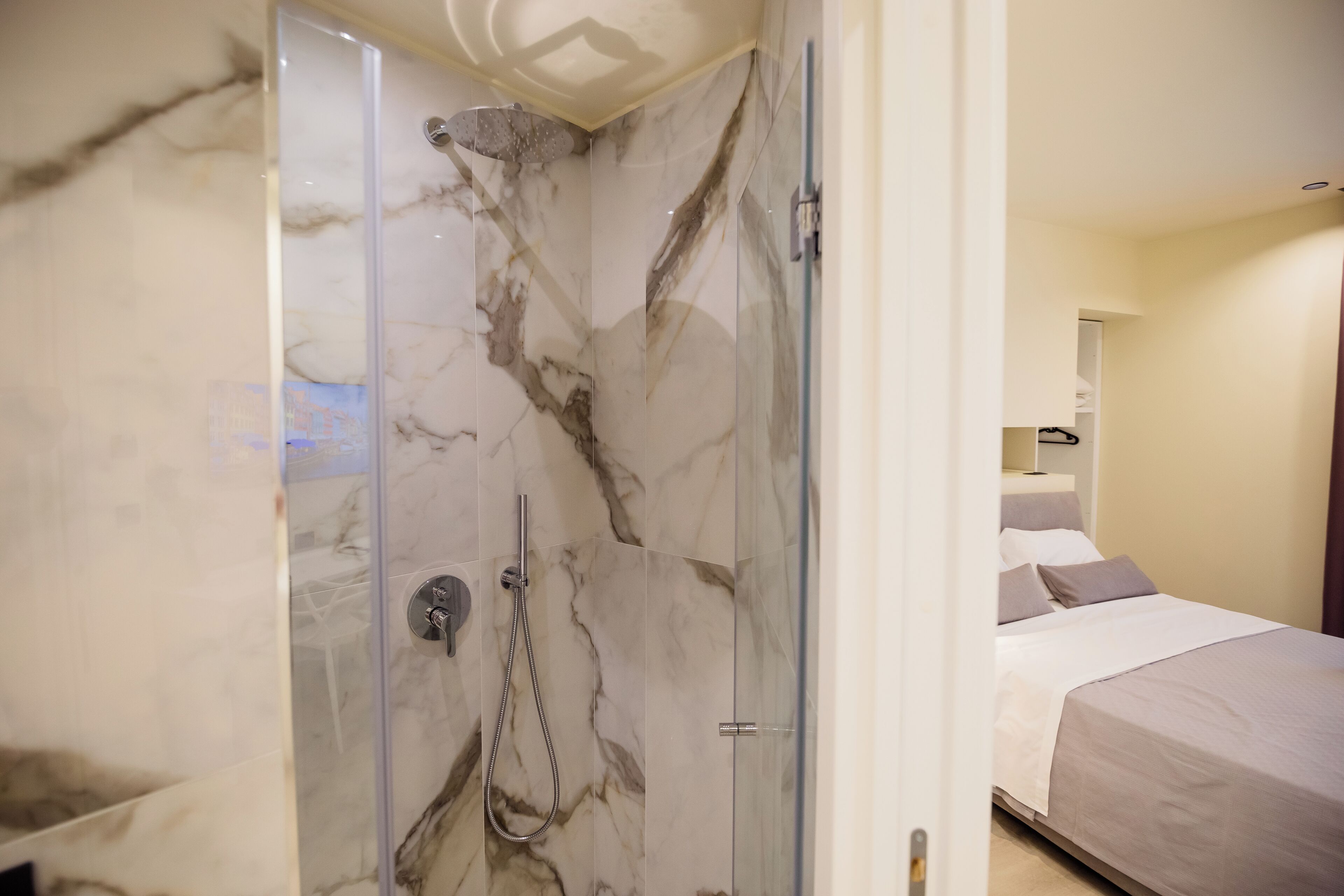 A modern bathroom with a glass-enclosed shower and marble walls.