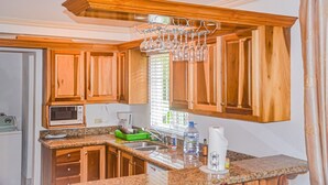 A kitchen with wooden cabinets, a microwave, a sink, and a wine rack. - Bamboo Villa  (St. Ann's Bay)