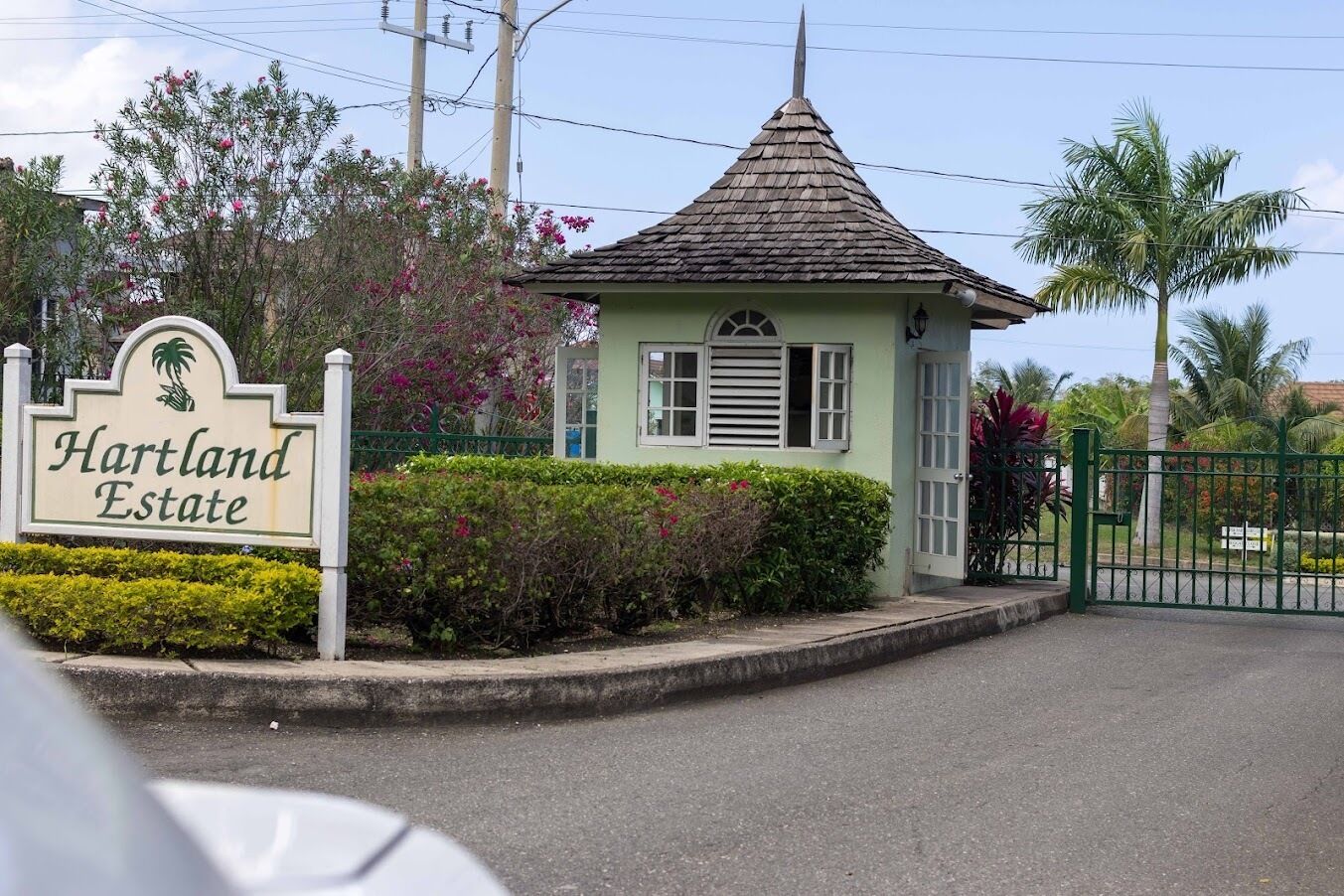 Uma entrada fechada para Hartland Estate, com um pequeno edifício e vegetação exuberante.