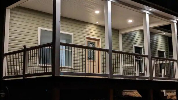 Une maison à deux étages avec un porche couvert et un balcon grillagé.