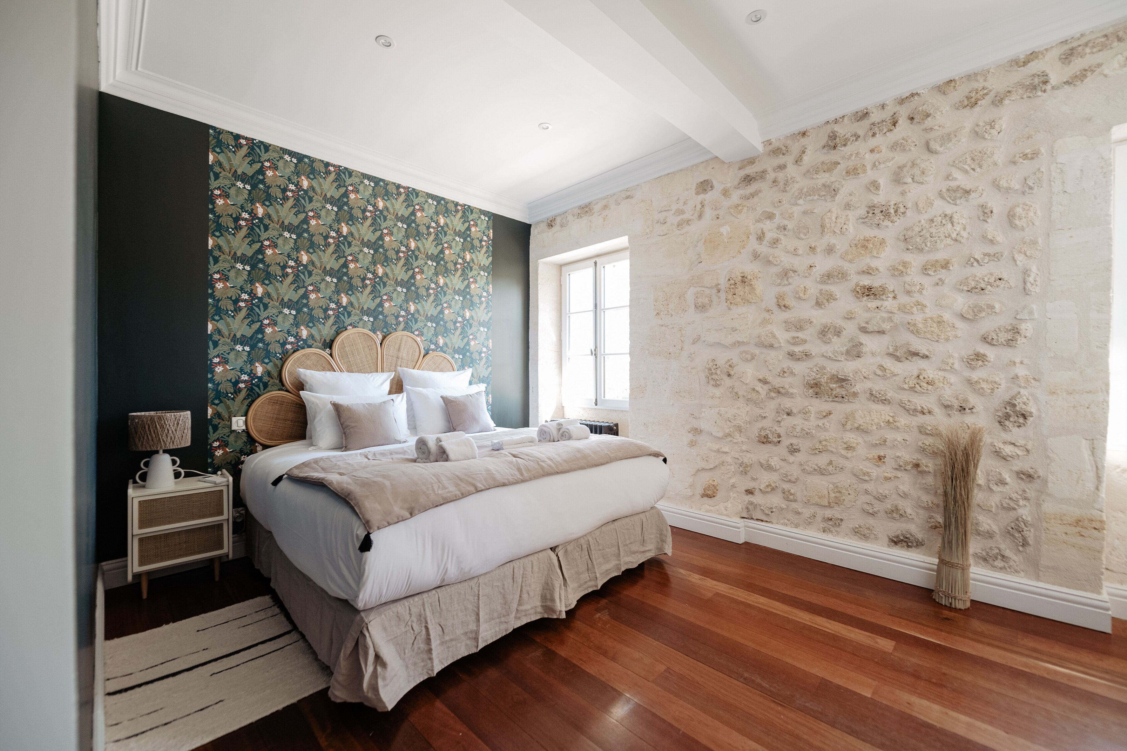 A bedroom with a bed, nightstands, a lamp, and a window.