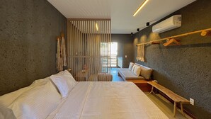 A modern bedroom with a large bed, a bench, and a wall-mounted air conditioner. - Villas Manatee by ER (Porto de Pedras)