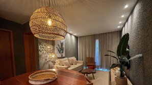 A modern living room with a wooden dining table, a sofa, and a large potted plant. - Villas Manatee by ER (Porto de Pedras)