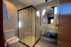 A modern bathroom with a glass-enclosed shower, a toilet, and a vanity with a mirror. - Villas Manatee by ER (Porto de Pedras)