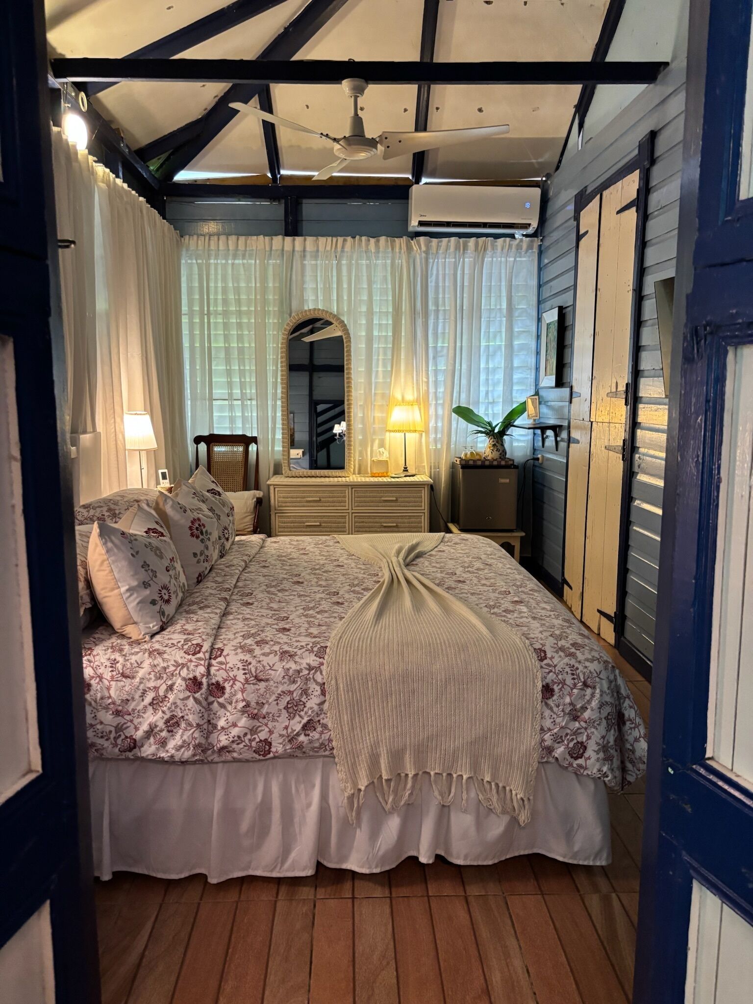Een slaapkamer met een bed, nachtlampjes, een kaptafel en een spiegel.