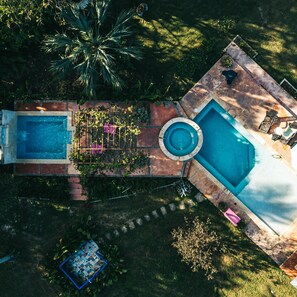 A rectangular swimming pool with a hot tub, surrounded by a brick patio and lush greenery. - Campito Loving (San Rafael del Yuma)