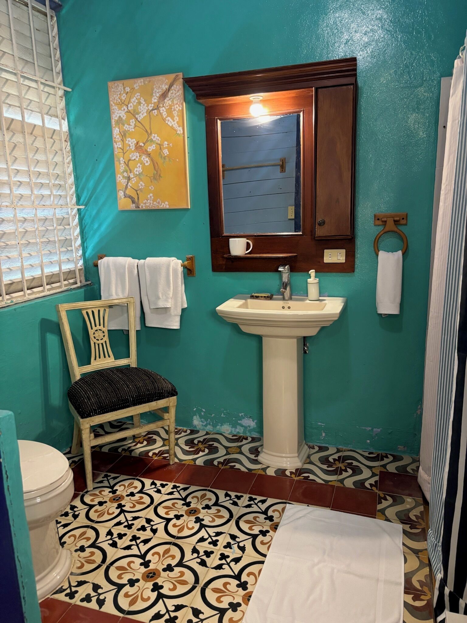 Un baño con inodoro, lavamanos, silla y zona de ducha.