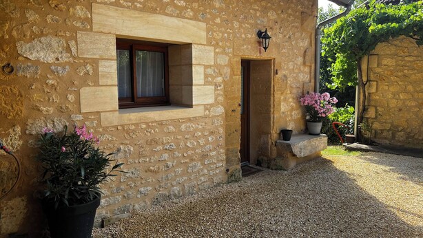 A stone building with a window, door, and potted plants.