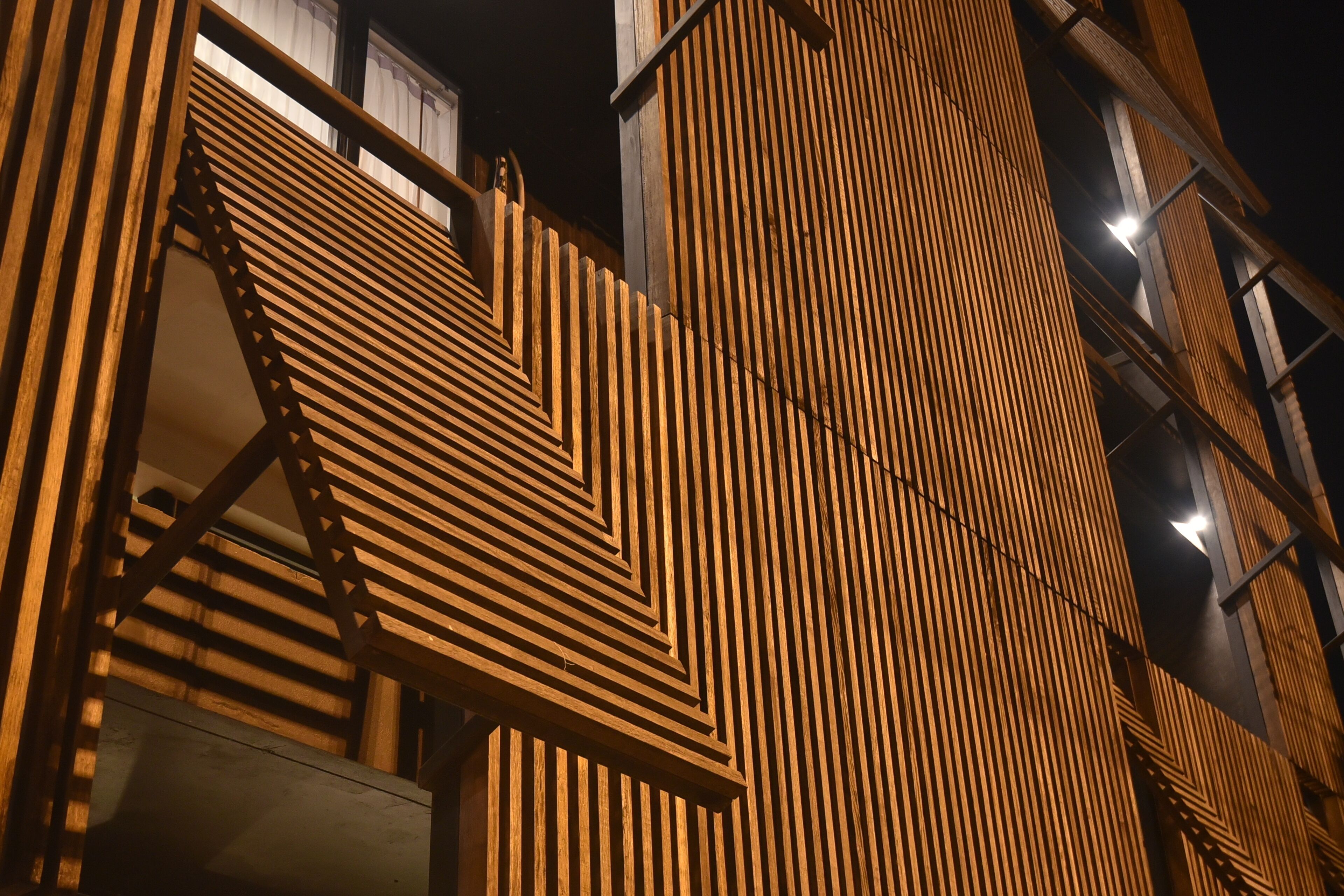 A building facade with a geometric wooden pattern and visible structural beams.