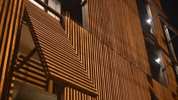 Fachada de edificio con un diseño geométrico de madera y vigas estructurales visibles.