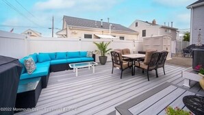 Eine überdachte Terrasse mit einem blauen Sofa, einem Tisch mit Stühlen und einem Blumentopf.