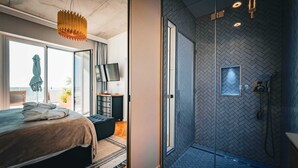 A modern bedroom with a large bed, a TV, and a view of the outdoors. - La maison Régent (Pornichet)